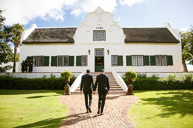 Cape Dutch Manor Gay Wedding Couple walk towards Manor House at Webersburg Wine Estate Stellenbosch Wedding Venue